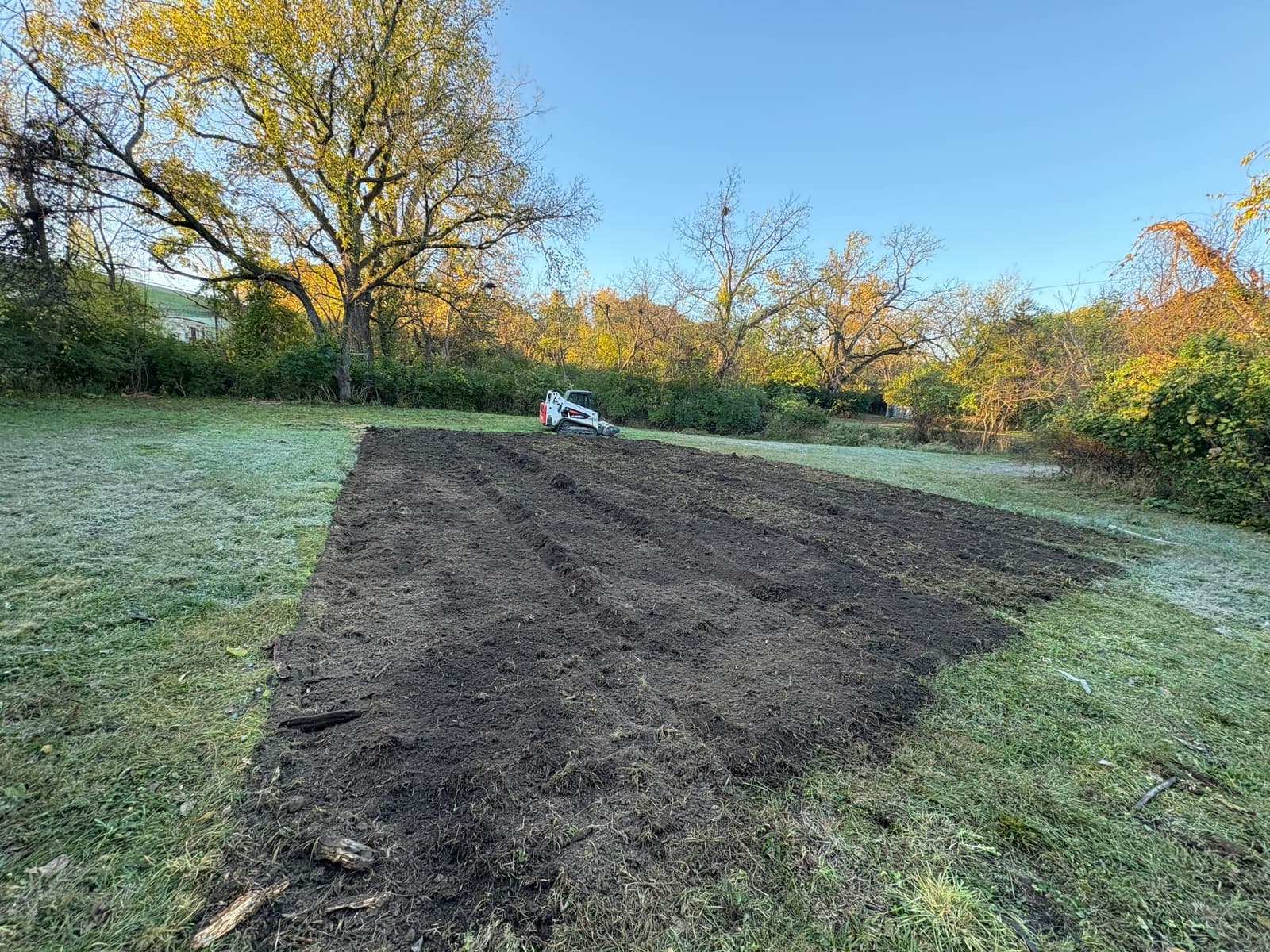 Skid steer clearing and grading a field down to bare ground